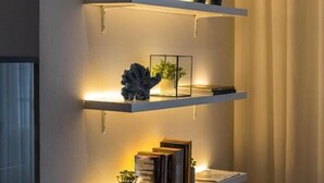 A wall-mounted shelf unit with three shelves, each holding decorative items and books. - Hotel Farol (Ilhavo)