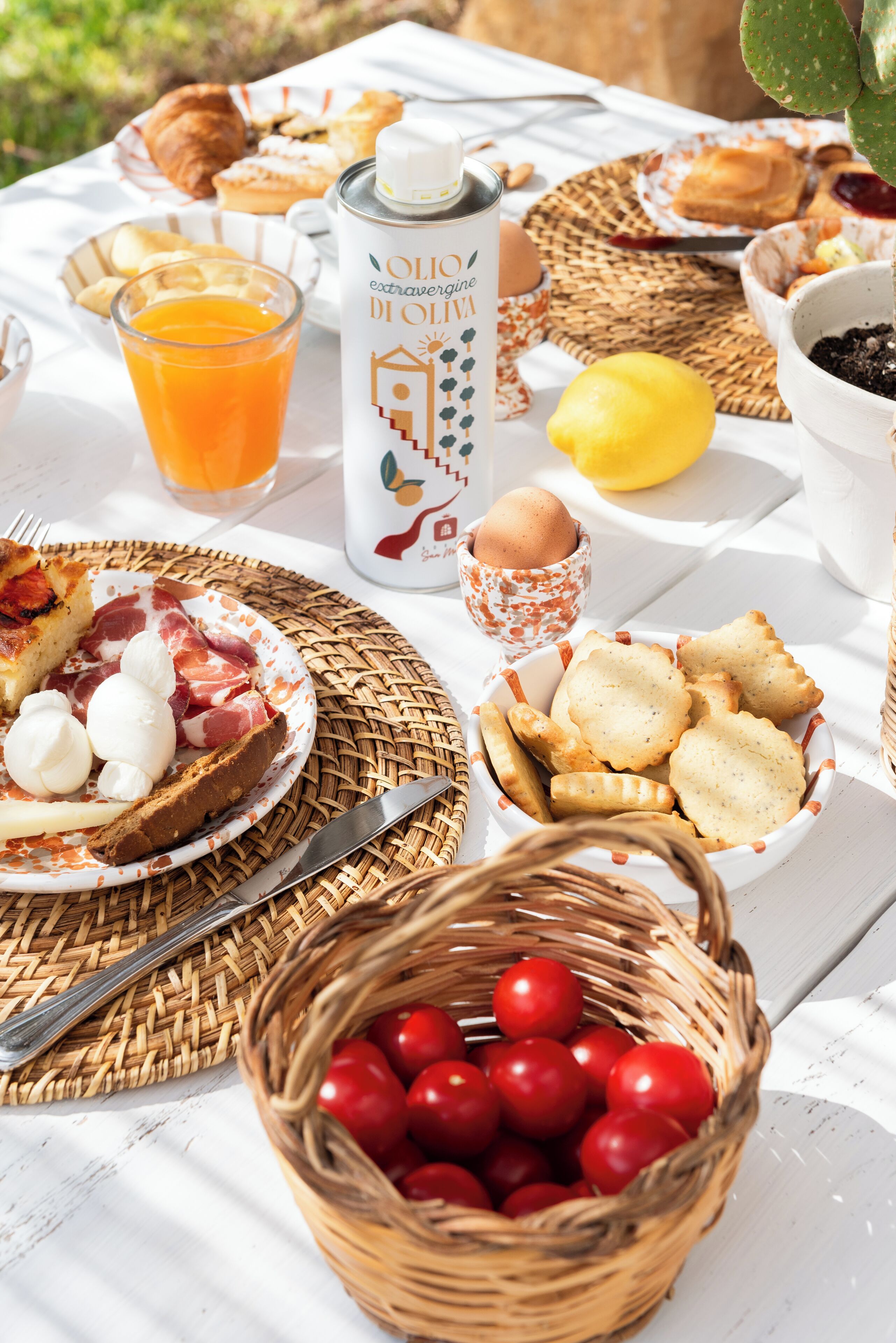 A table set with breakfast items including bread, eggs, and a basket of cherries.