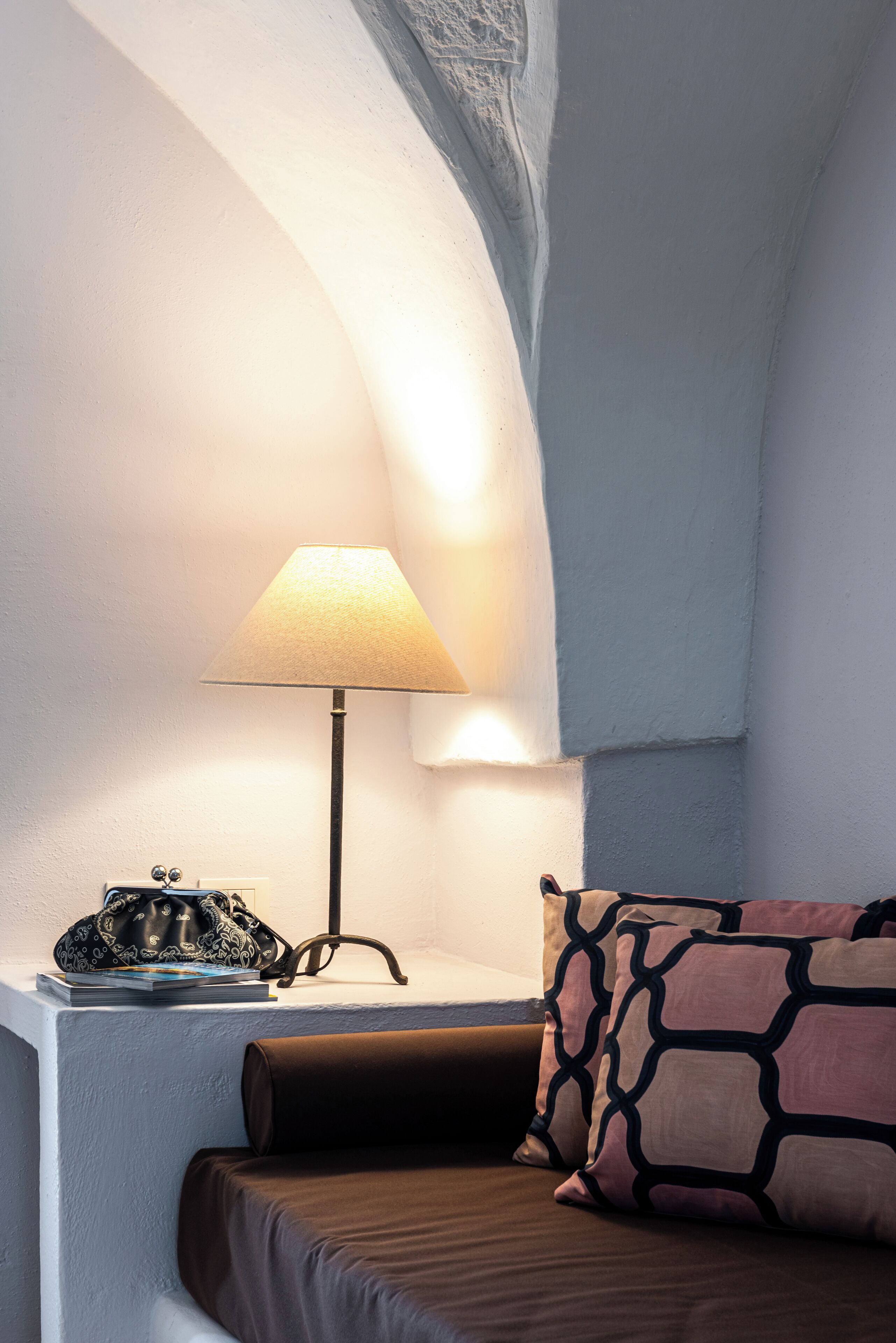 A cozy bedroom with a bed, a lamp, and a nightstand.