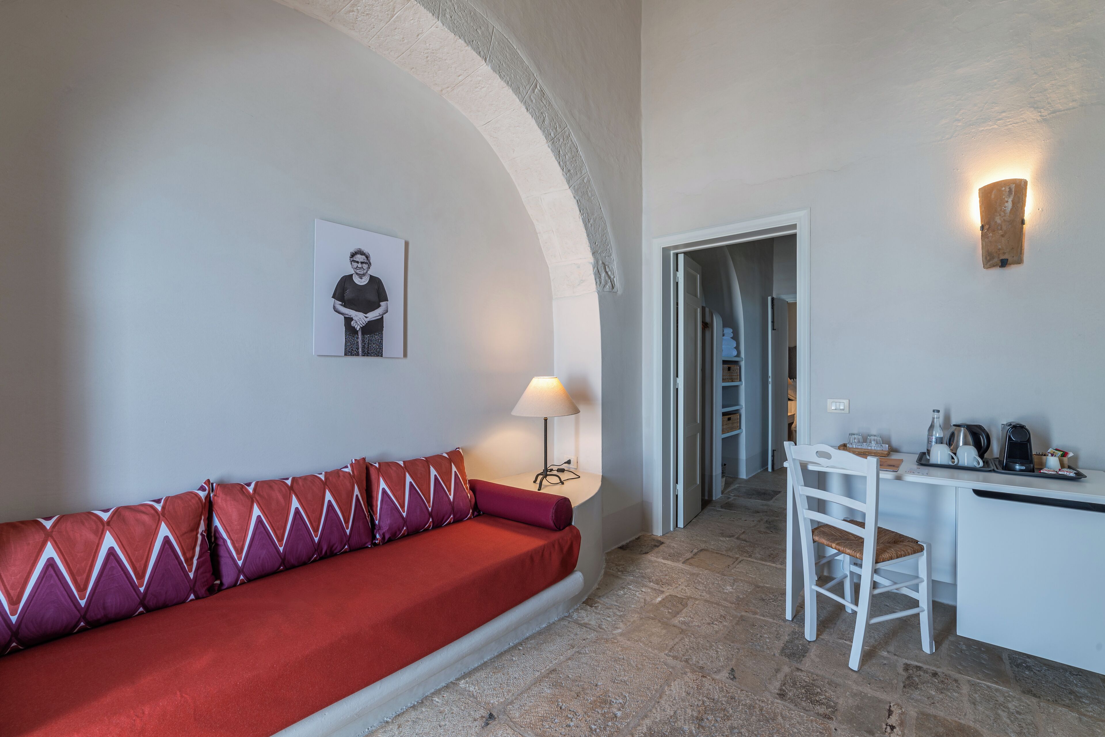 Una habitación acogedora con un sofá rojo, una mesita con lámpara y una silla.