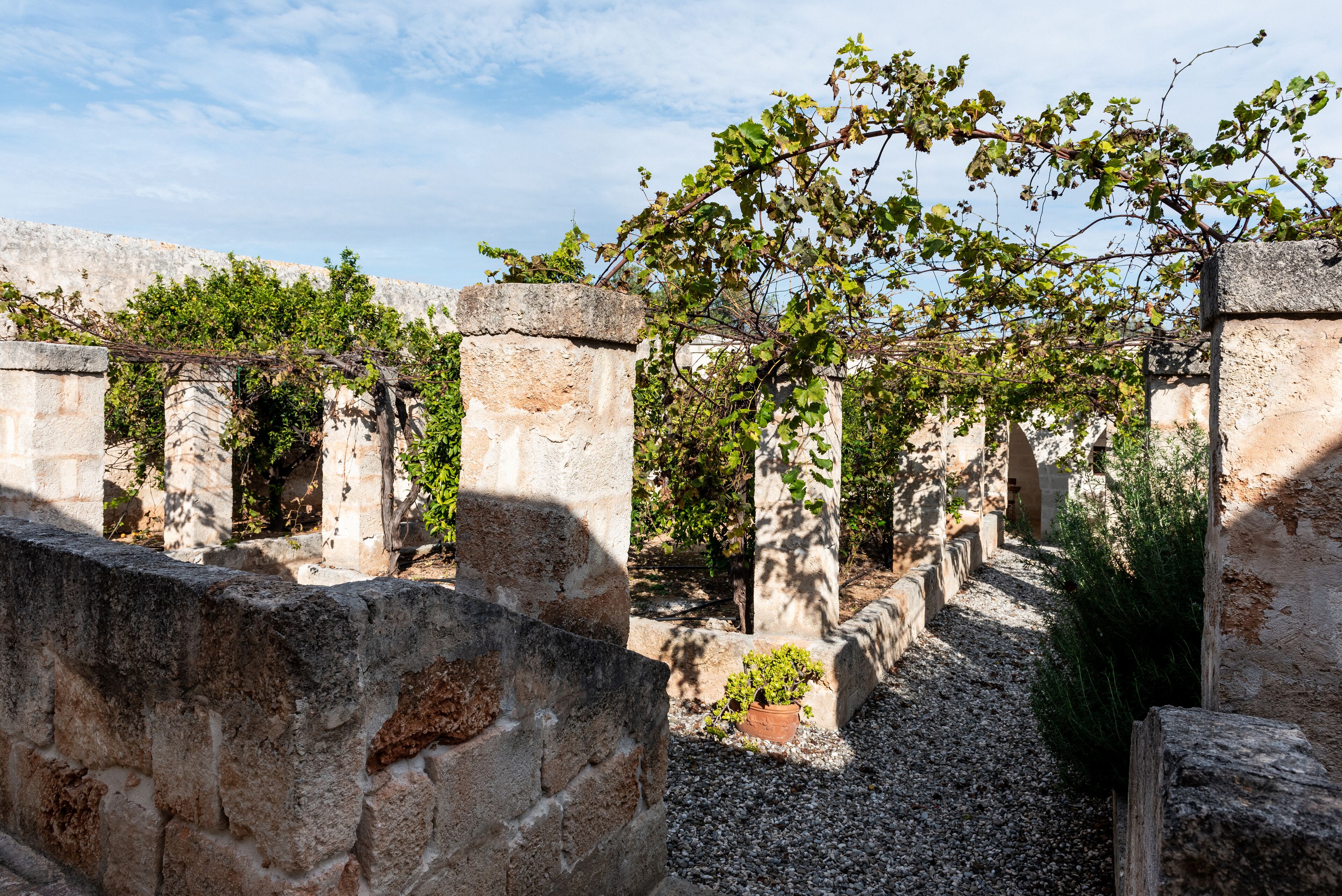 An ancient stone structure with arches and a gravel path.