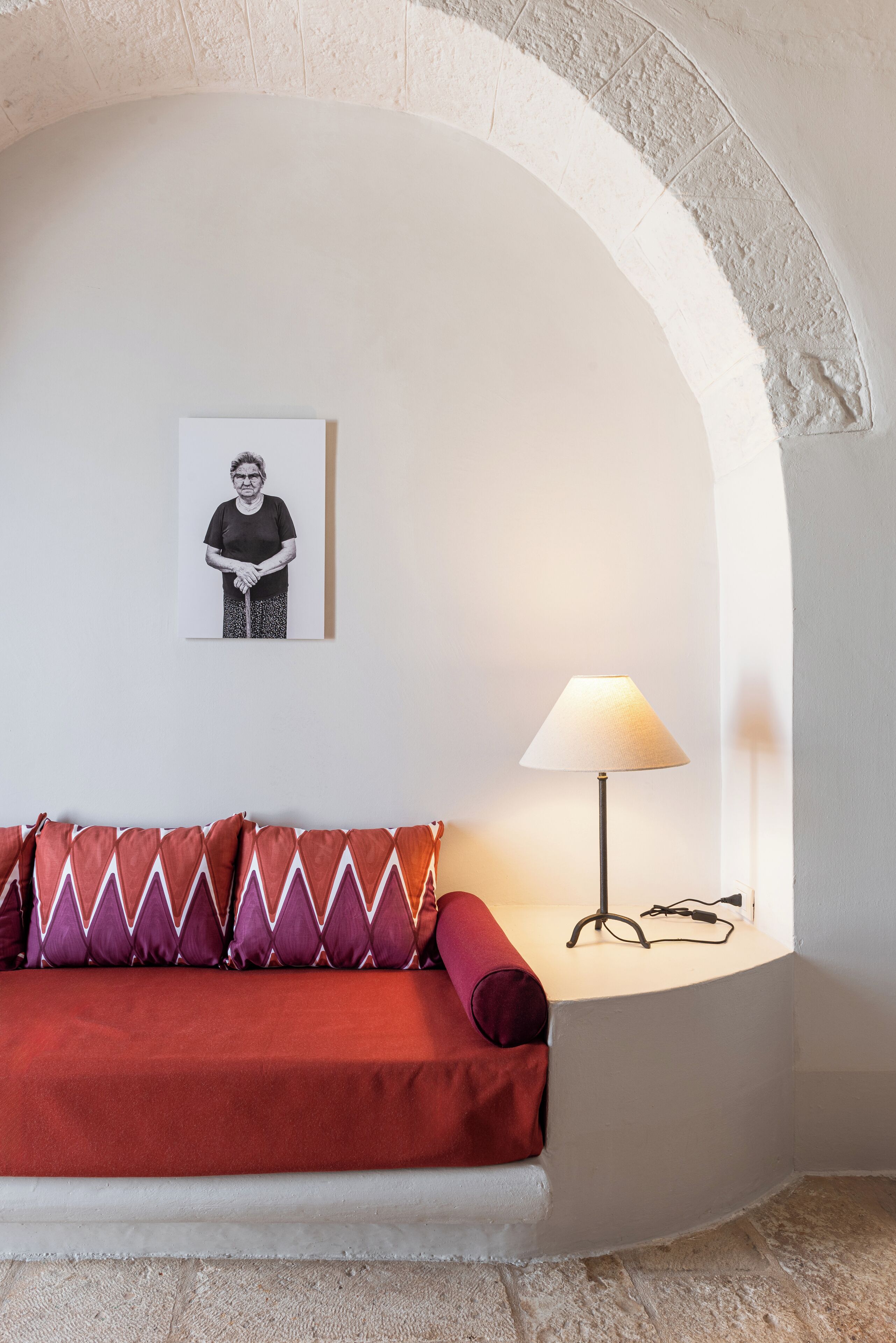 A cozy room with a red sofa, a lamp, and a framed picture on the wall.