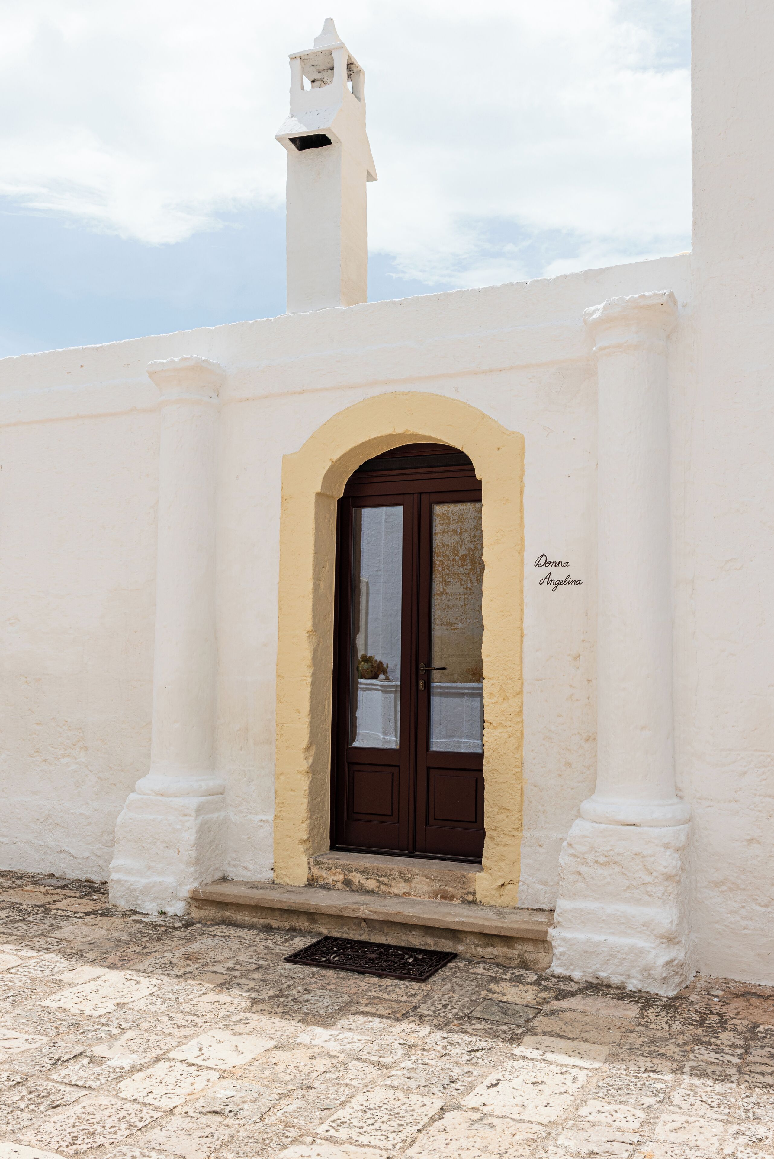 A white building with a brown door and a small bell tower.