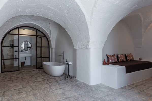 Un baño moderno con una bañera independiente, un espejo grande y un banco empotrado con almohadones.