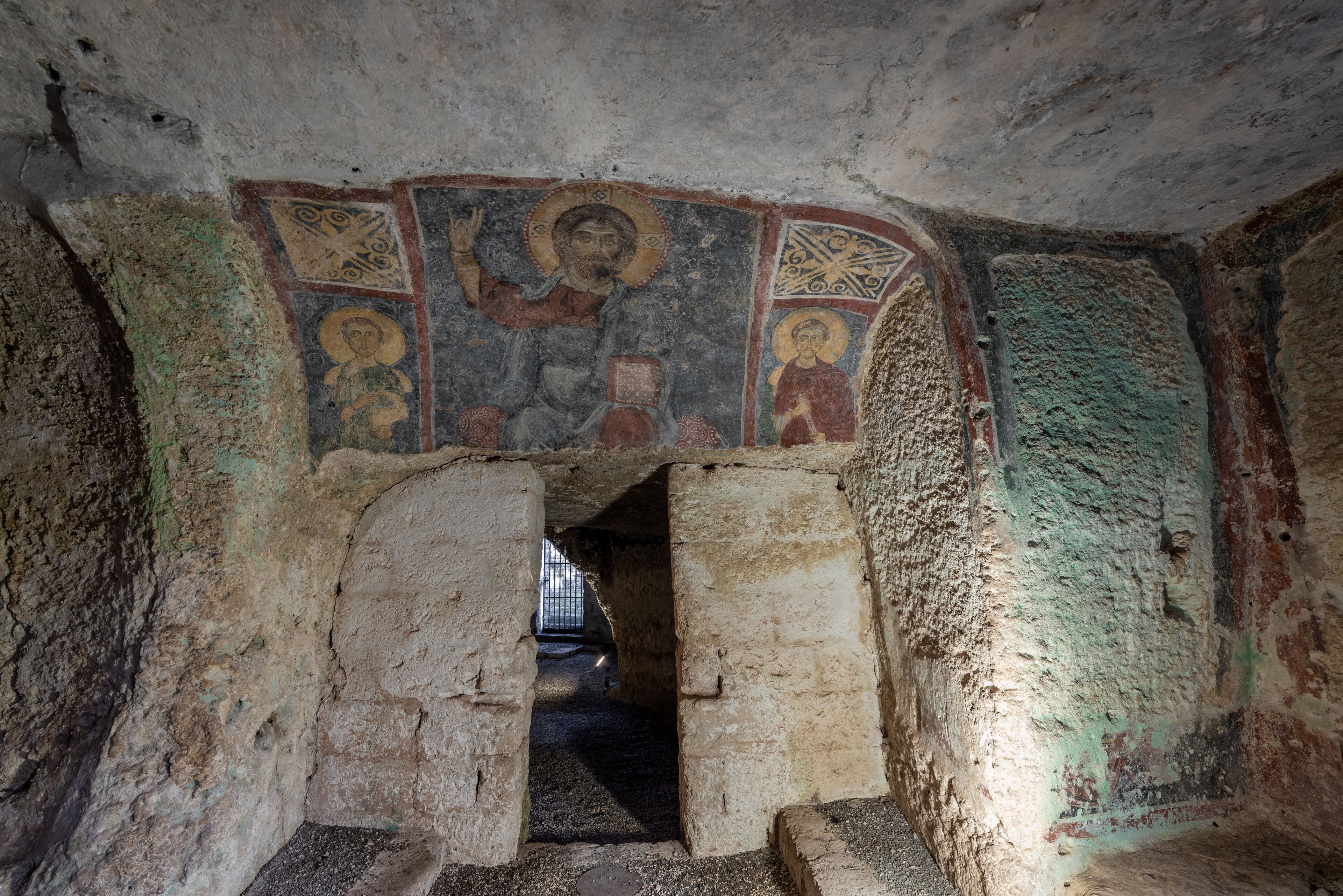 Un arco di pietra antica con affreschi religiosi.