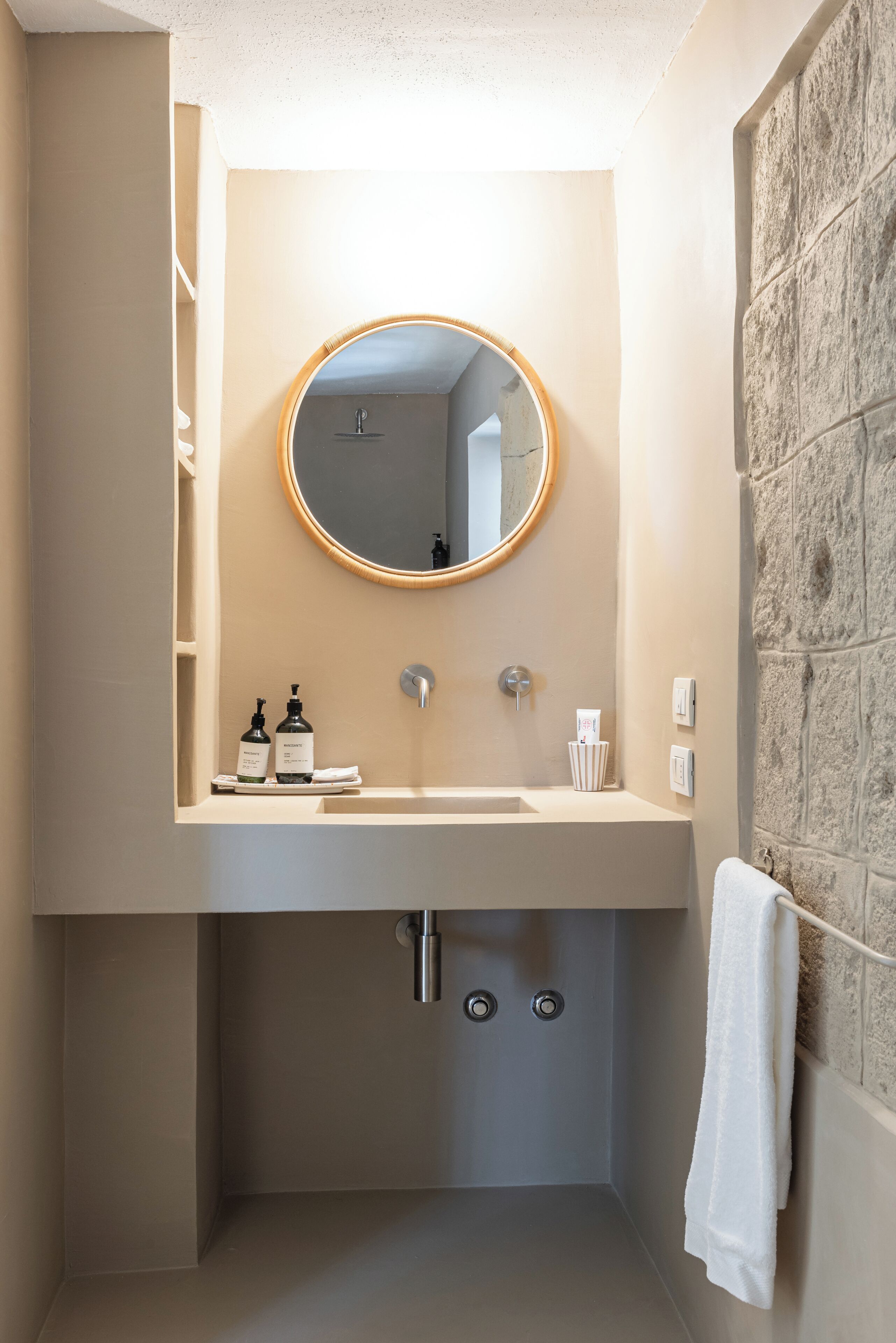 A bathroom with a round mirror, a sink, and a towel rack.