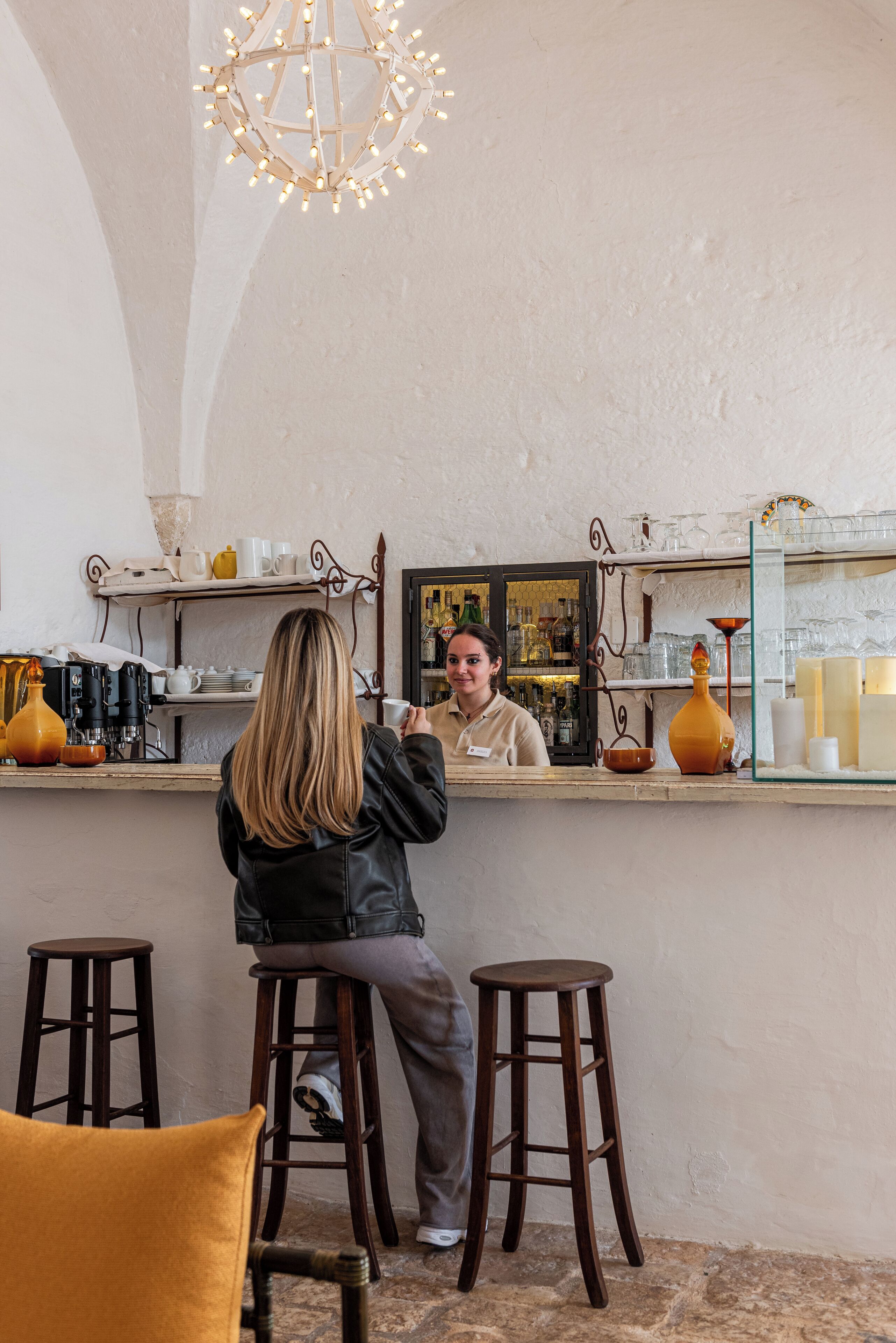 Zona de bar con taburetes, una barra y una lámpara colgante.