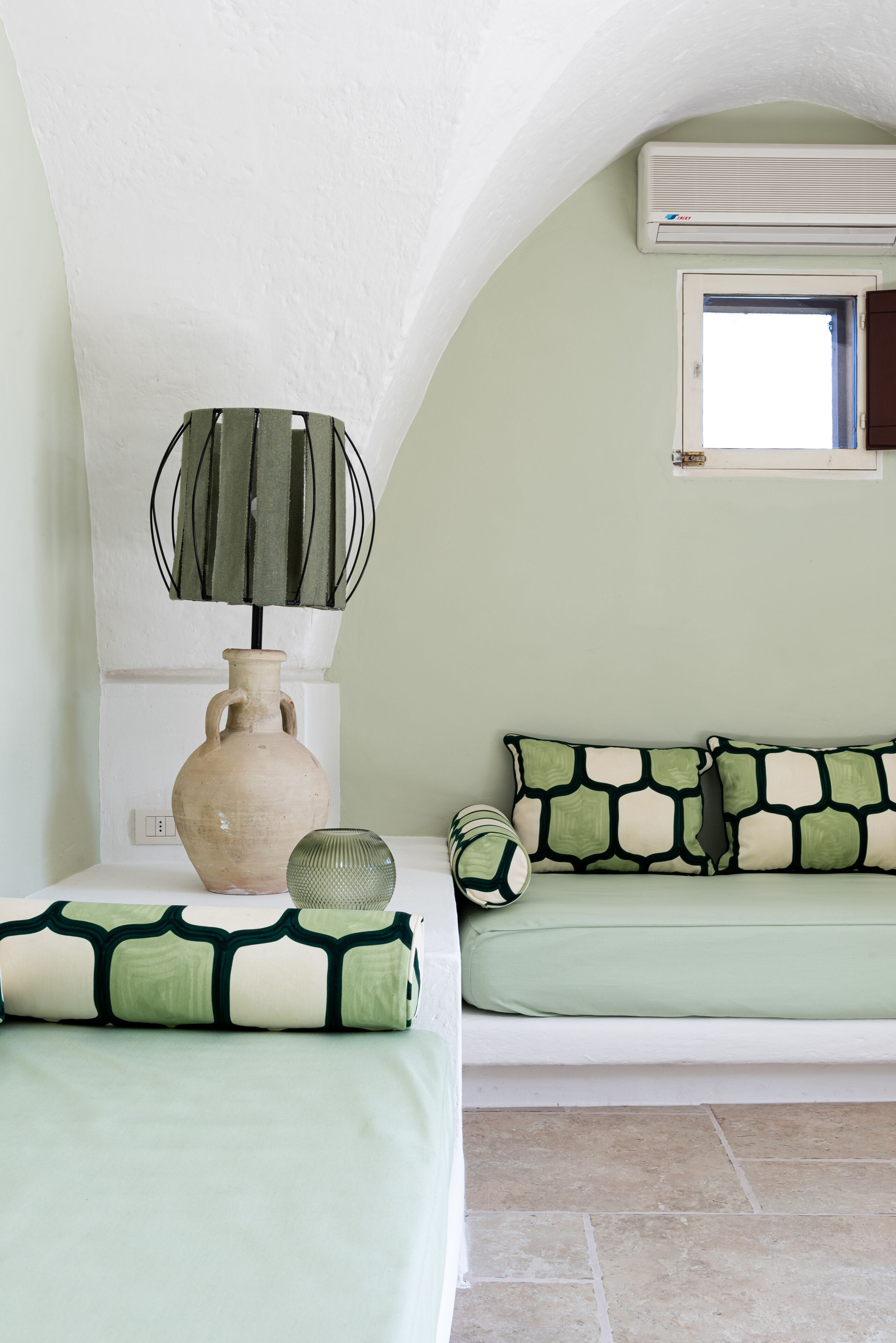 Une chambre à coucher avec un lit, un vase et un climatiseur fixé au mur.
