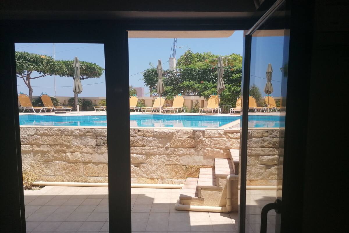 A poolside area with stone walls, tiled flooring, and sun loungers.
