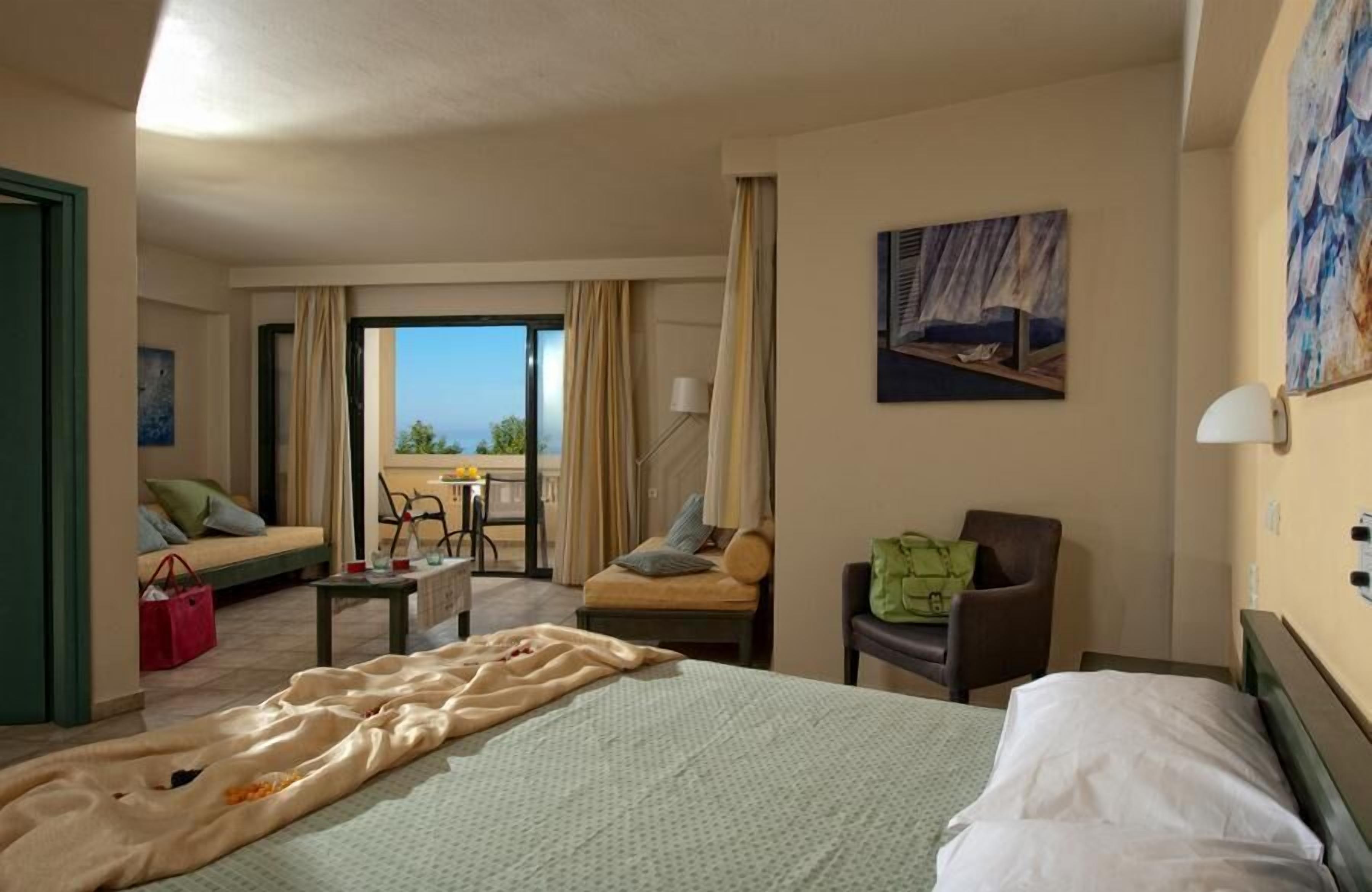A hotel room with a bed, a chair, a sofa, a table, and a view of the outdoors.