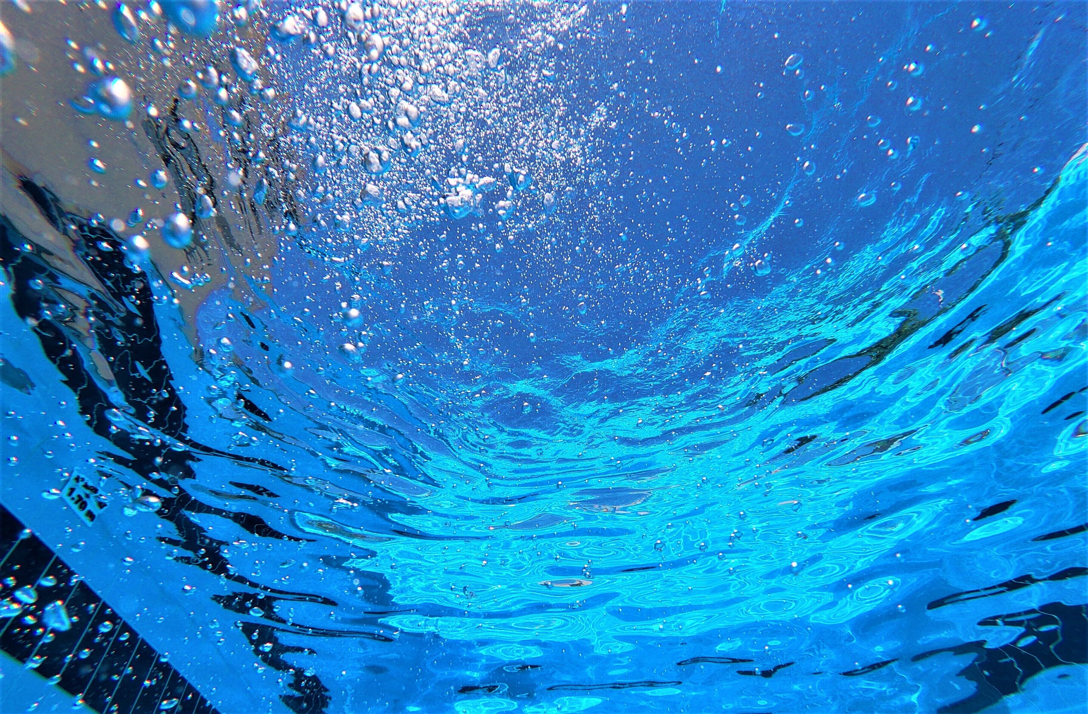 An underwater view of a swimming pool with clear water and bubbles.