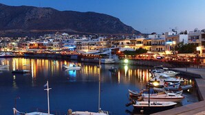A marina with boats docked, a waterfront promenade, and buildings with illuminated windows.