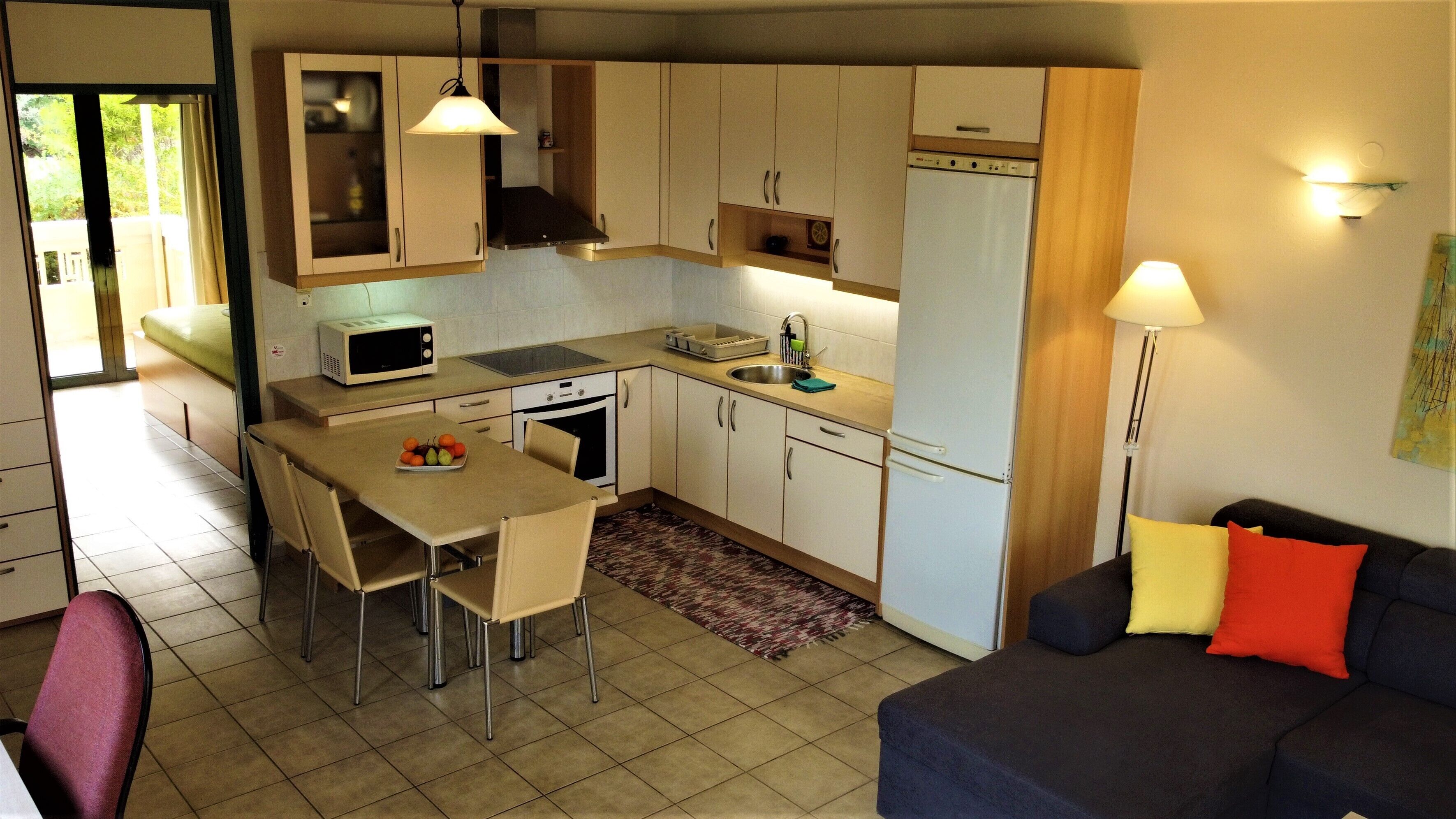 A compact kitchen with a dining area, a refrigerator, a microwave, and a sink.