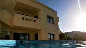 A swimming pool with clear water, a building with balconies, and a mountain in the background.