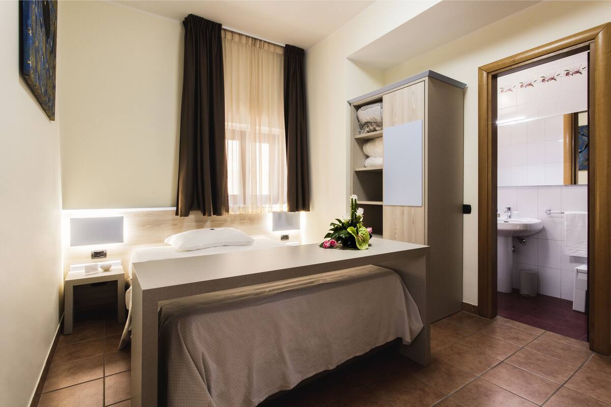 Une chambre d’hôtel avec un lit, une table de chevet, une lampe et une vue sur la salle de bain.