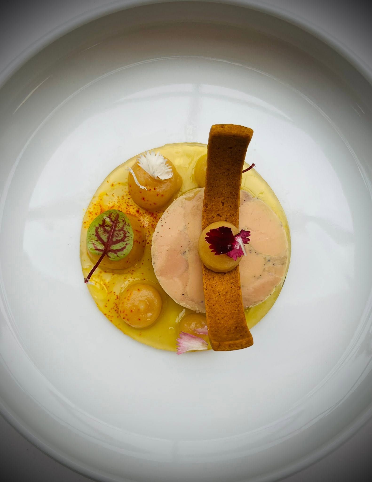 Une assiette blanche avec un plat principal au centre, entouré de petites portions et de quelques accompagnements.