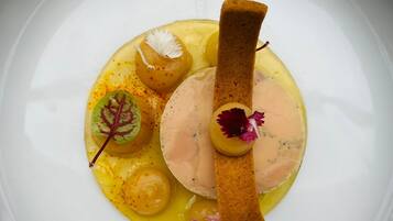 Une assiette blanche avec un plat principal au centre, entouré de petites portions et de quelques accompagnements.