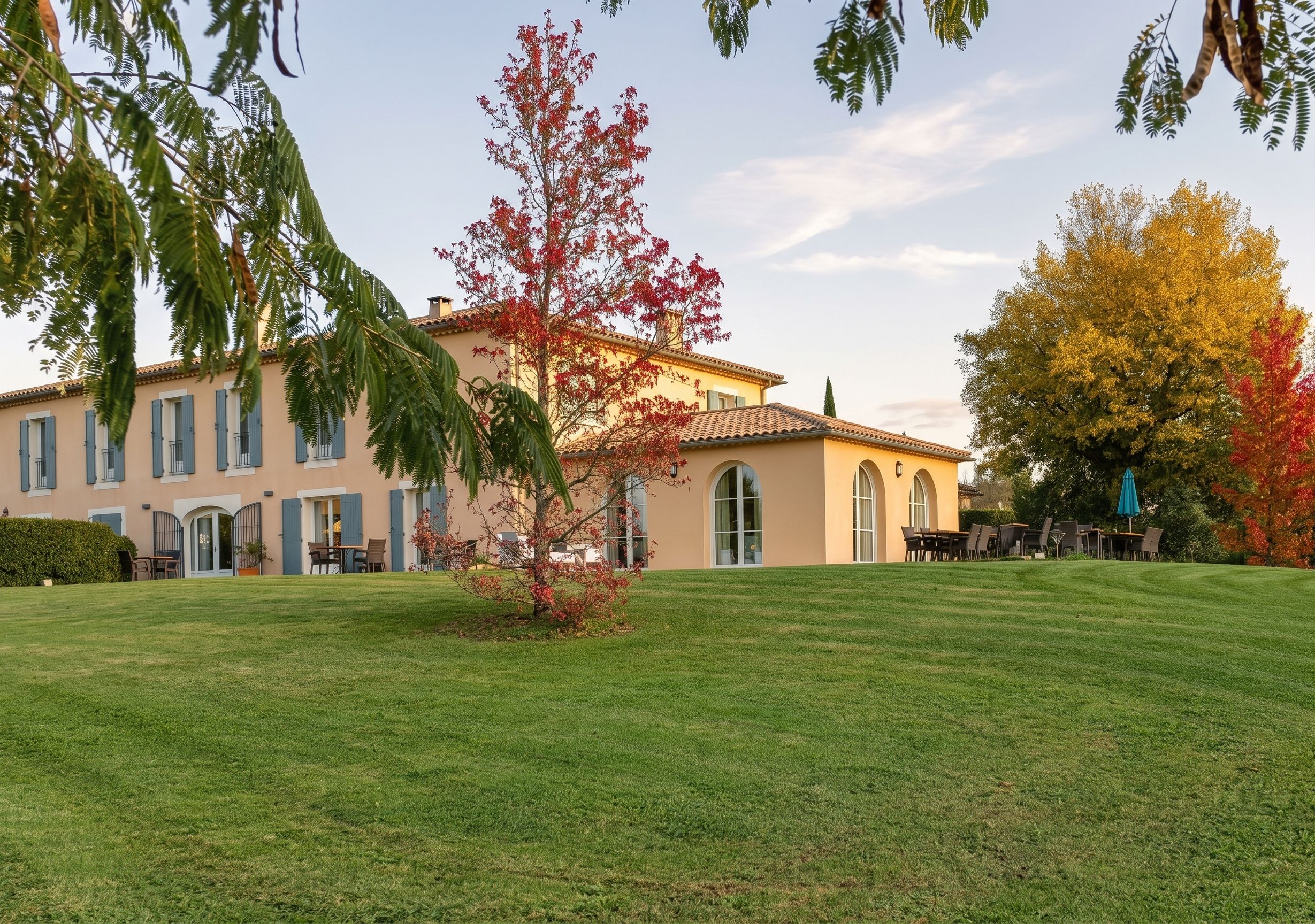 Un bâtiment à la façade symétrique, doté de grandes fenêtres et bordé d’une pelouse bien entretenue.