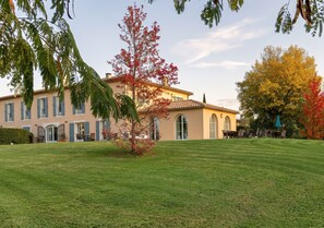 A building with a symmetrical facade, large windows, and a well-maintained lawn. - Hôtel La Bastide d'Iris (Vagnas)
