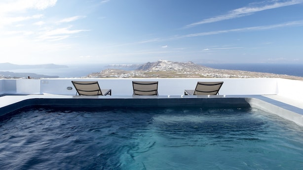 A infinity pool with three chairs facing a scenic view of a mountainous landscape and the sea. - Villa Fabrica Santorini (Santorini)