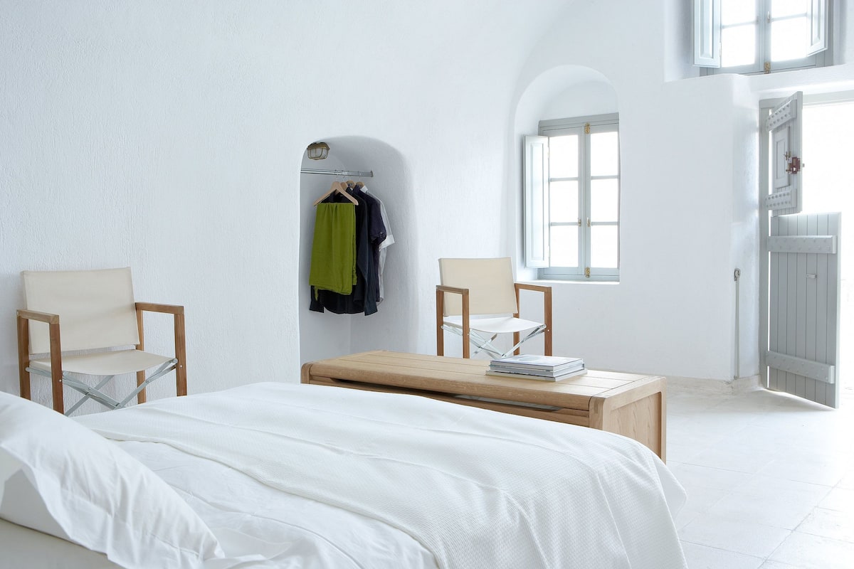 Une chambre à coucher avec un lit, deux chaises, une petite table et une fenêtre.
