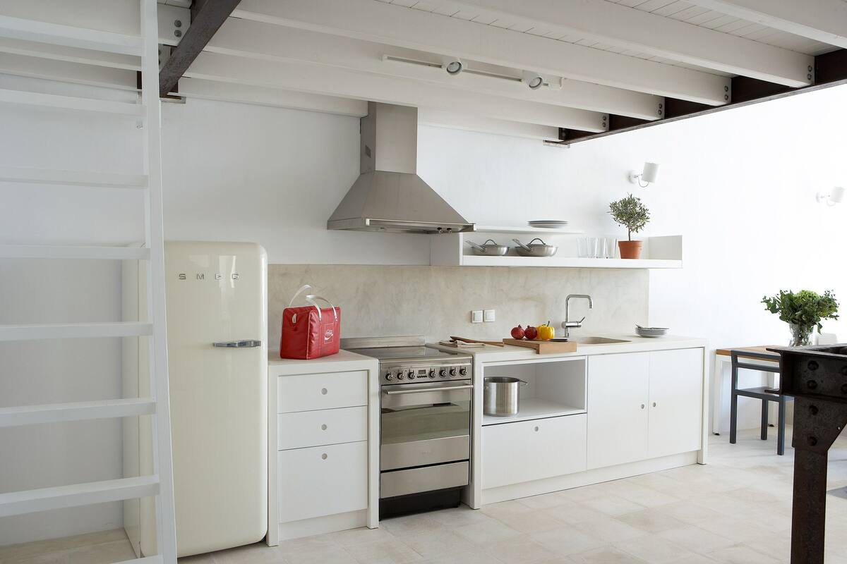 Une cuisine moderne avec des meubles blancs, une cuisinière en acier inoxydable et un four encastré.