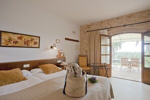 Habitación de hotel con cama, un cuadro, una lámpara, una silla y vistas al exterior.