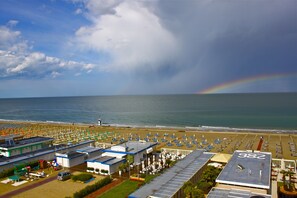 A beachside hotel with a large parking area, beach umbrellas, and a view of the ocean. - Hotel Centrale (Cervia)