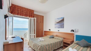 Une chambre d’hôtel comprenant un lit, un bureau, une chaise, une armoire et un balcon avec vue sur la mer.
