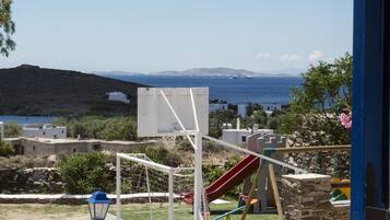Enjoy a safe and enjoyable outdoor play area with a basketball hoop, slide, and play structures, surrounded by lush greenery and a stone wall.