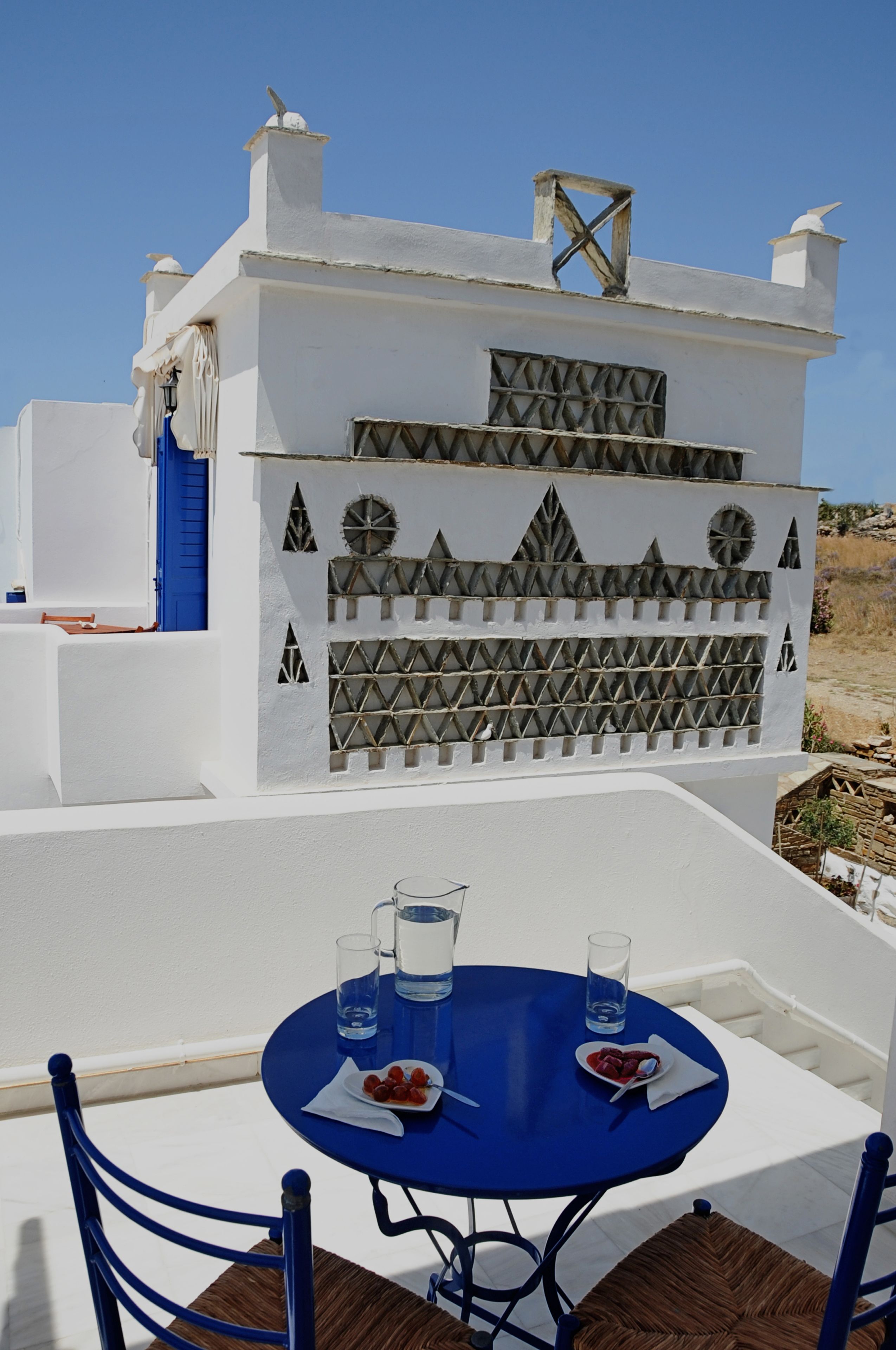 A white building with blue accents and a blue table with chairs.