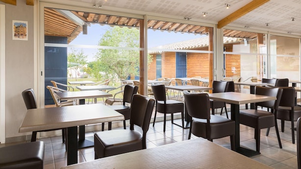 Un restaurante con terraza, vigas de madera y grandes ventanales.