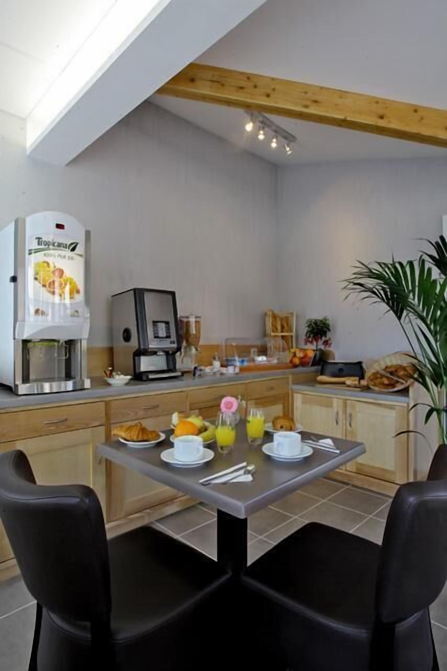 A modern kitchen with a coffee machine, a fruit bowl, and a dining table with chairs.