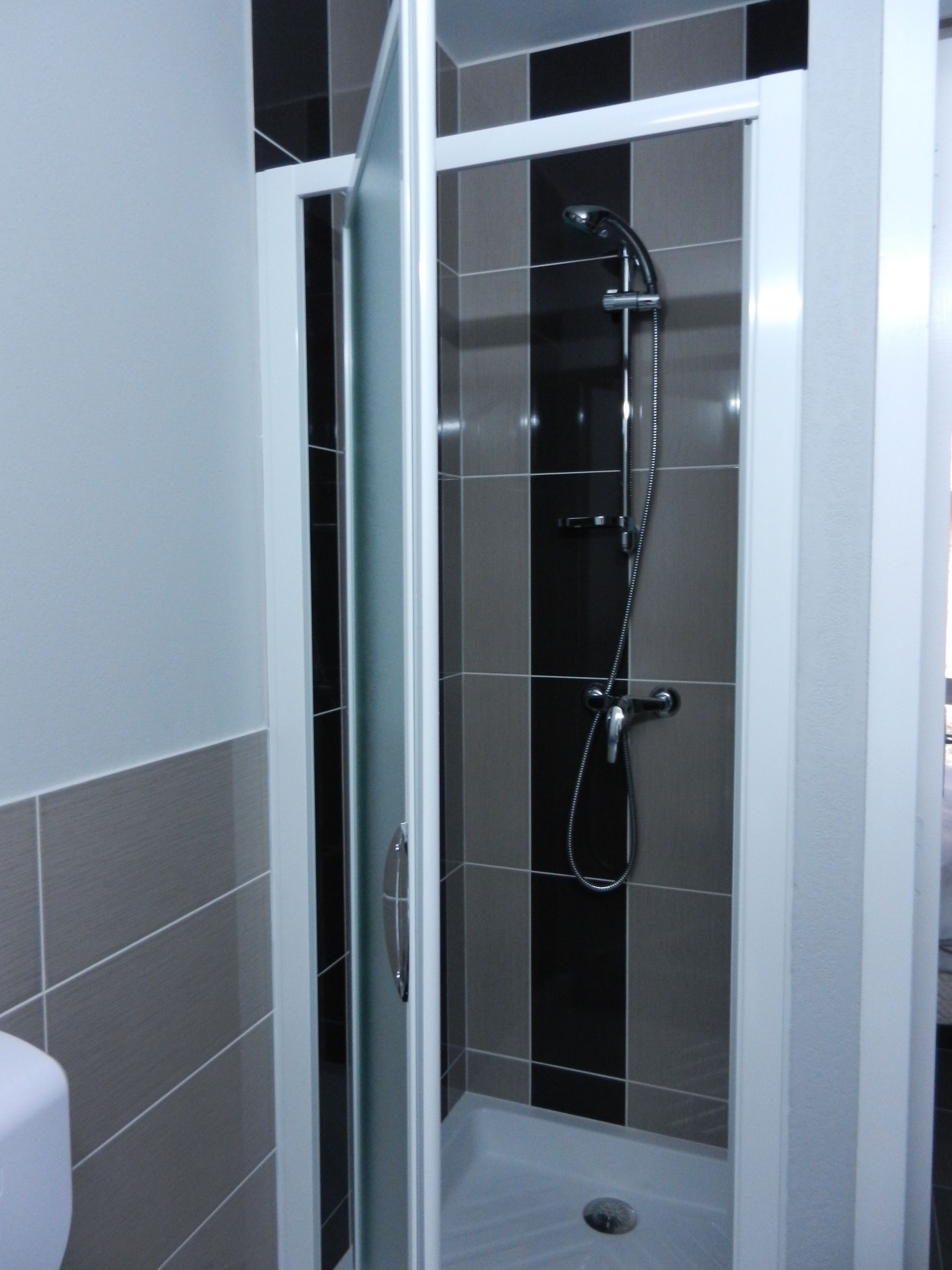 A walk-in shower with a glass door, tiled walls, and a showerhead.