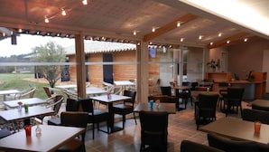 Un restaurante con terraza, mesas y sillas de madera.