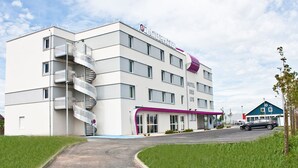 Un hotel moderno con facciata bianca, una caratteristica scala a chiocciola e un tendone viola.