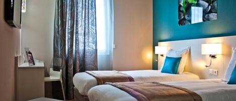 A hotel room with two beds, a TV, a desk, and a window with curtains.