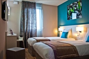 Una habitación de hotel con dos camas, televisión, escritorio y ventana con cortinas.