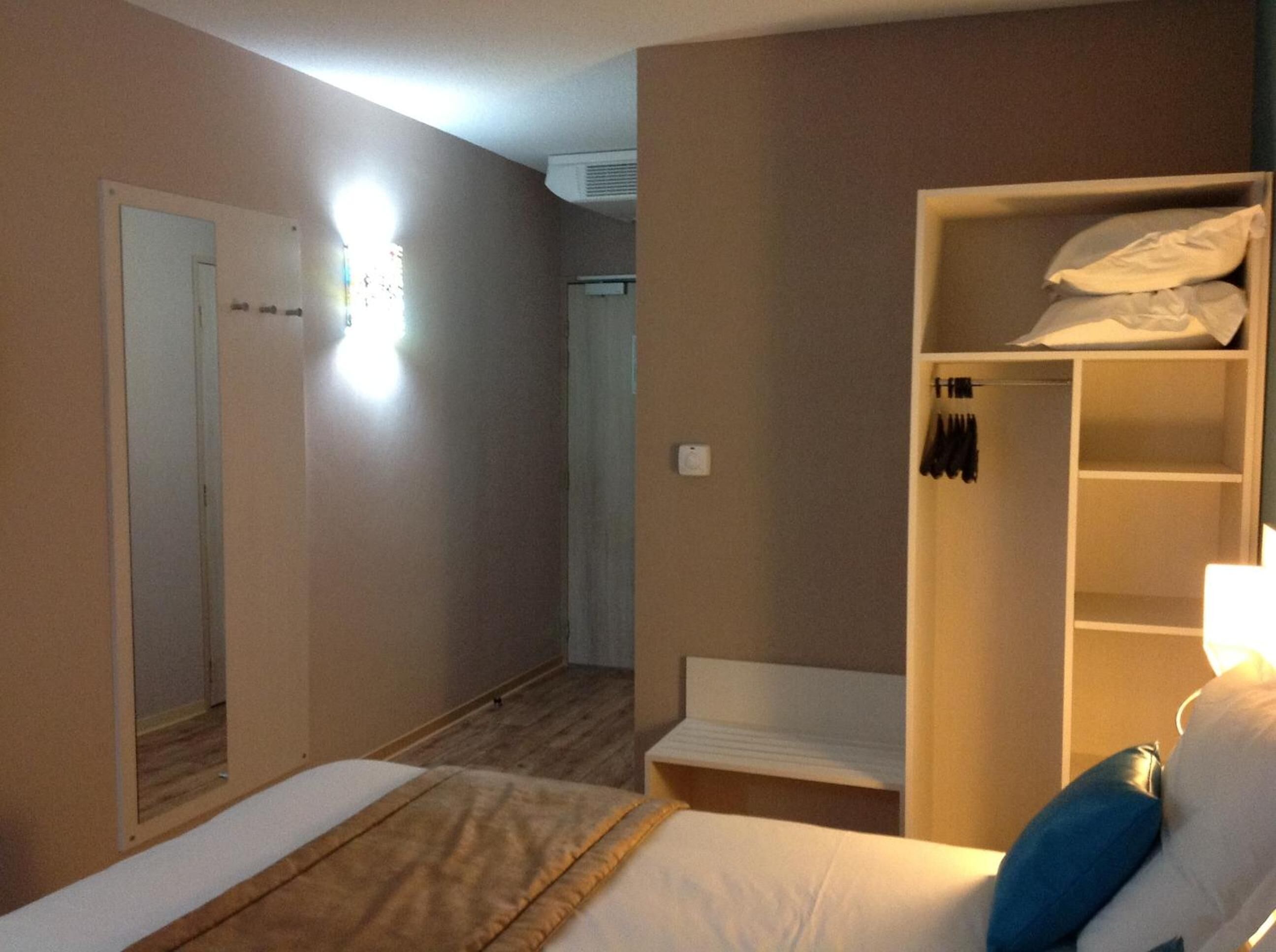 Une chambre d’hôtel avec un lit, une armoire et un miroir.