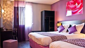Habitación de hotel con dos camas, un armario, un escritorio y un amplio ventanal con cortinas.