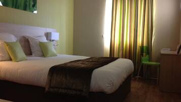 Una habitación de hotel con cama, escritorio, lámpara y cortina.