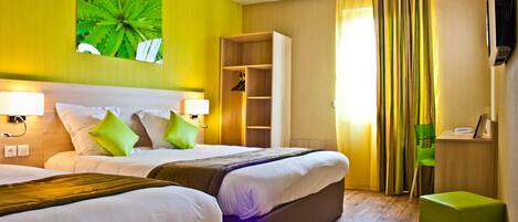 A hotel room with two beds, a wardrobe, a desk, and a green chair.