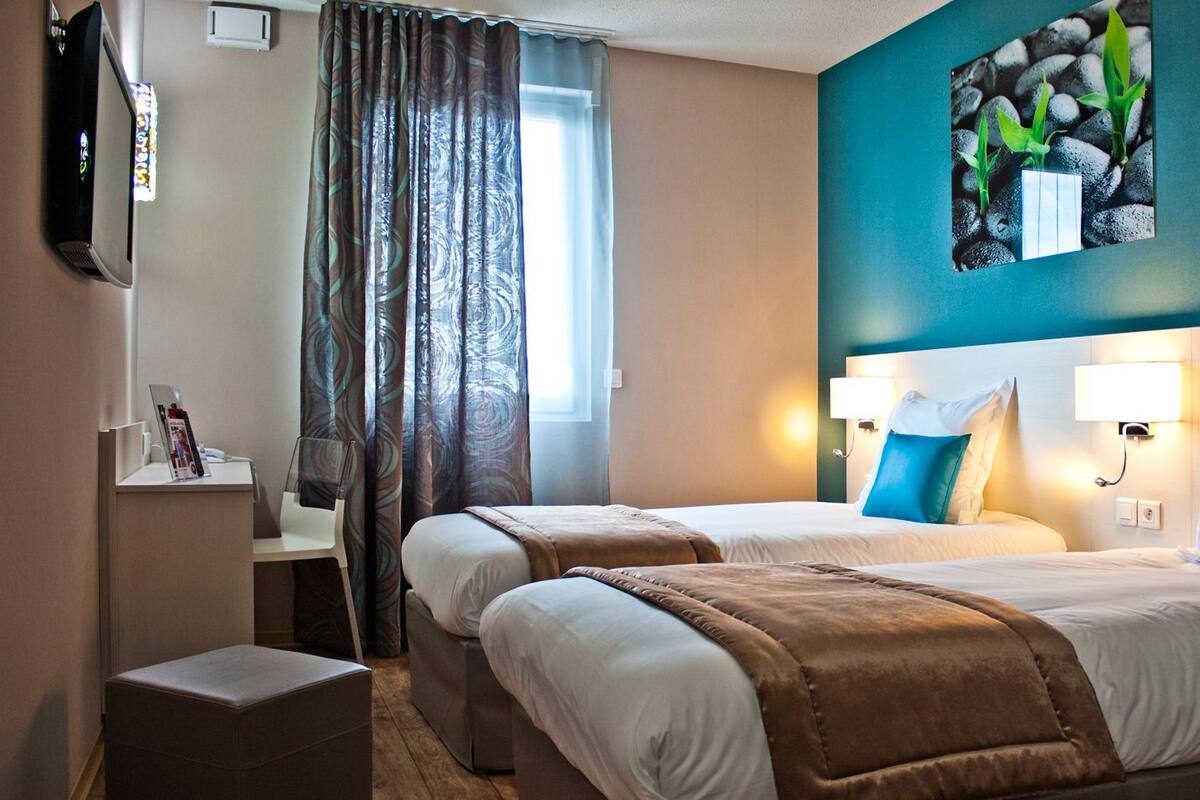 Une chambre d’hôtel avec deux lits, un bureau, une chaise, une télévision et un tableau au mur.