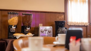 A breakfast bar with coffee machines, a coffee grinder, and a bread basket. - Hotel Estefania (Morelia)