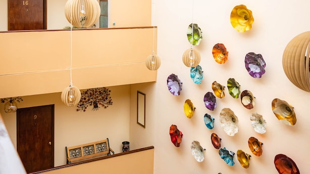 A multi-level interior with hanging spherical light fixtures and a wall adorned with colorful, abstract glass art. - Hotel Estefania (Morelia)