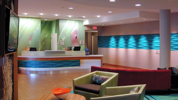 A reception area with a counter, seating, and a decorative wall. - SpringHill Suites Las Vegas North Speedway (North Las Vegas)
