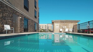 A swimming pool with clear blue water, surrounded by stone walls and a modern building. - SpringHill Suites Las Vegas North Speedway (North Las Vegas)