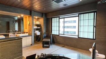 Un baño moderno con una bañera grande, zona de ducha, área de estar y un ventanal con vistas al exterior.