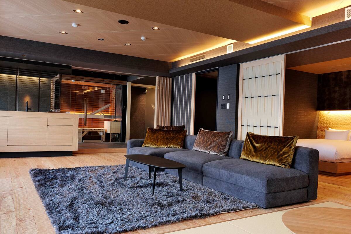 A modern living room with a grey sofa, a black coffee table, and a grey shag rug.