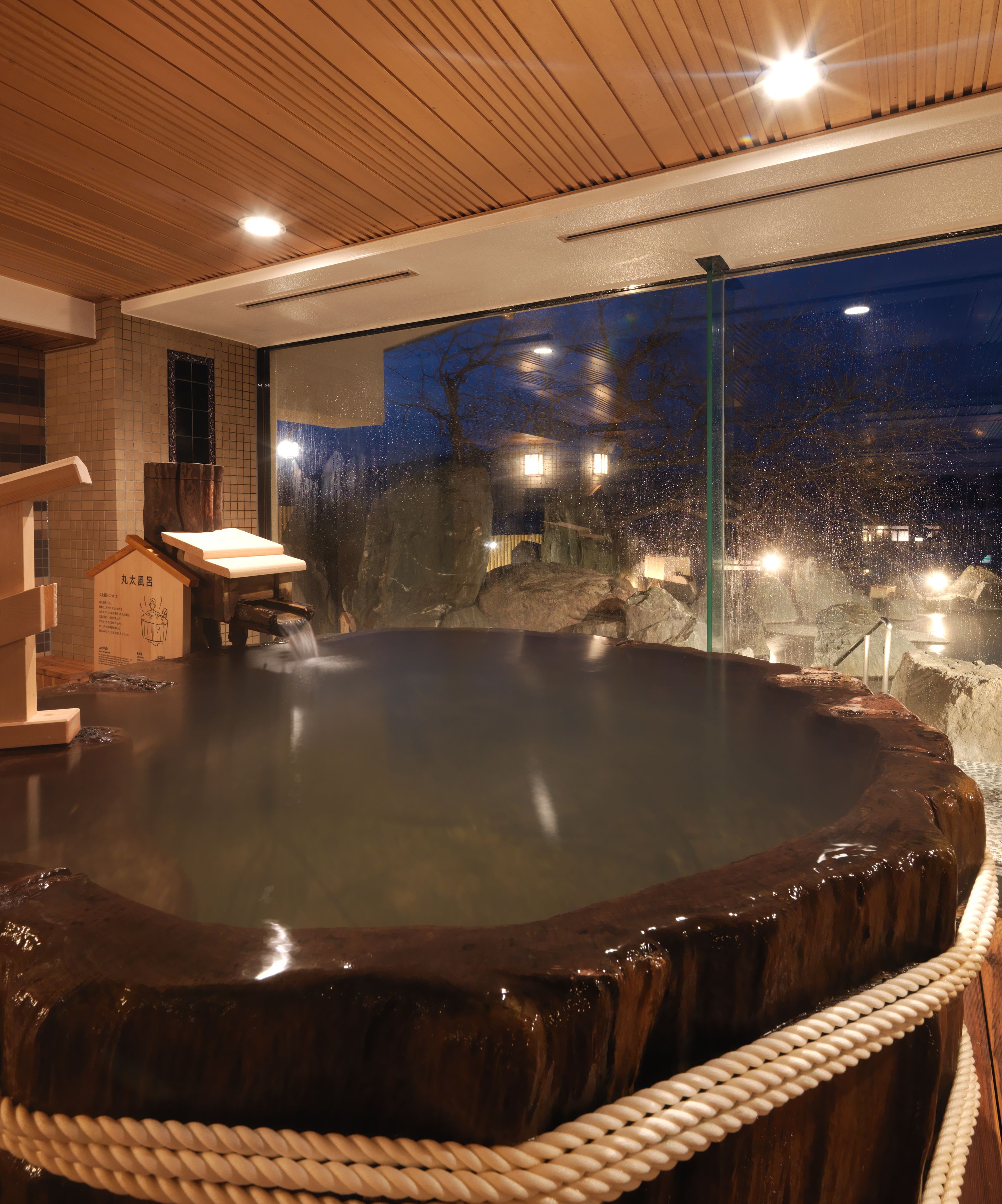 A hot spring bath with a wooden bench and a rope barrier.